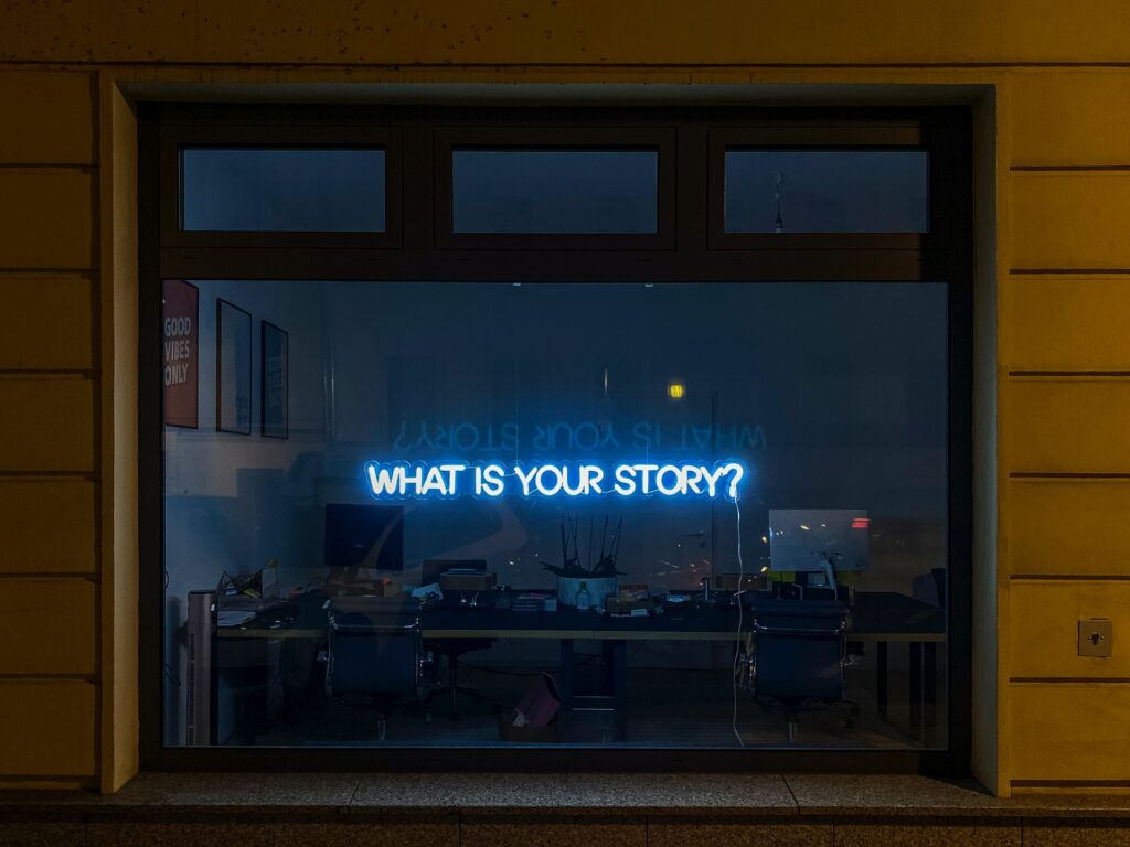 Neon lights on window spelling "What is Your Story?"